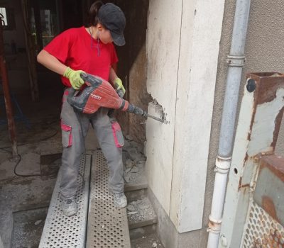 Emeline manie un marteau-piqueur sur un chantier de maçonnerie MEYER.