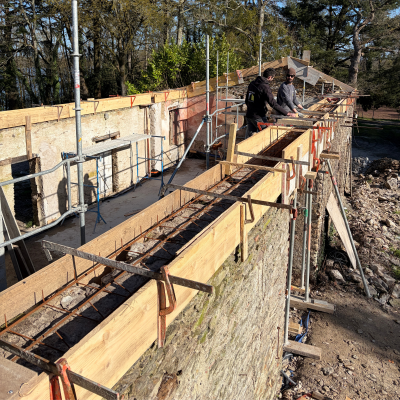 Mise en place et coulage d'un chaînage périphérique en béton armé sur un chantier de maçonnerie.